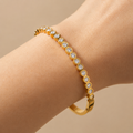 A gold-plated bracelet for women featuring a continuous row of bezel-set crystals and a secure side clasp, shown on a model hand