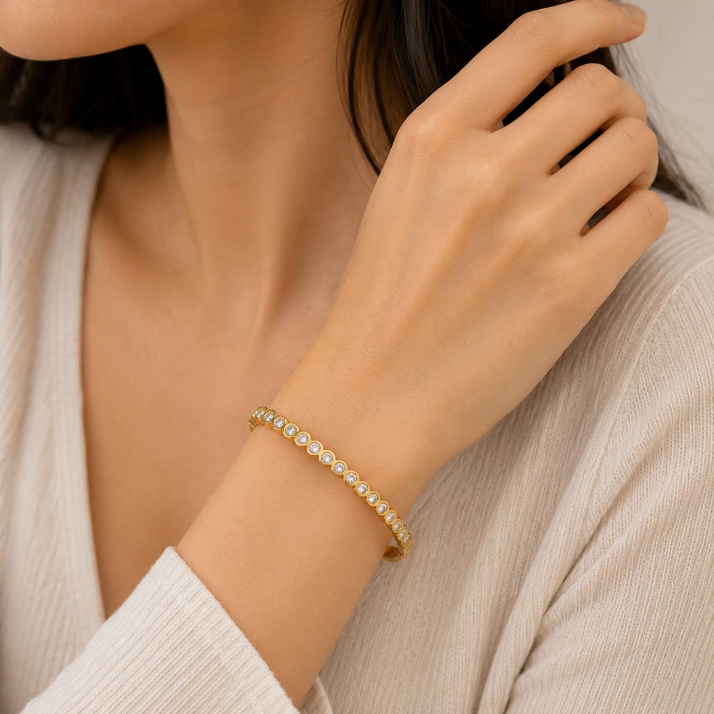 A gold-plated bracelet for women featuring a continuous row of bezel-set crystals and a secure side clasp, shown on a model