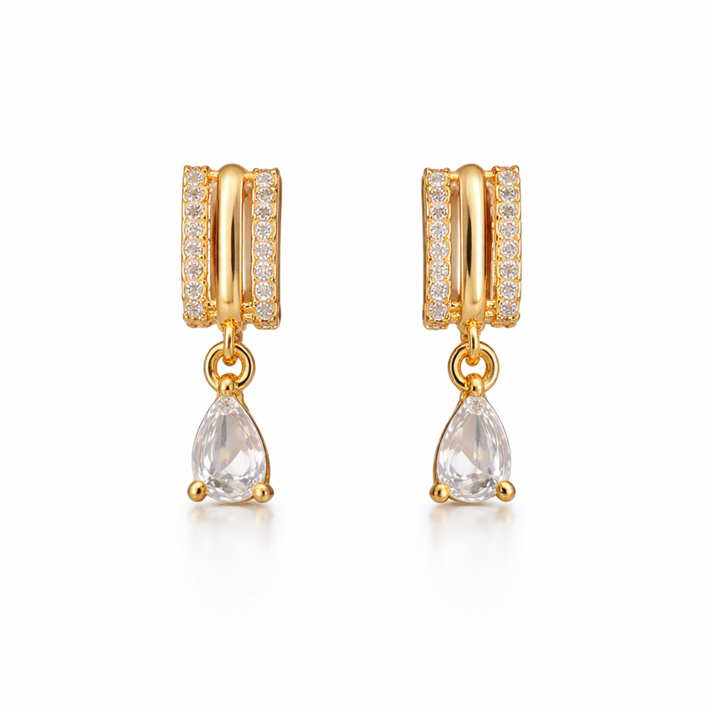 A pair of gold-plated huggie hoop earrings for women featuring a suspended clear pear-shaped crystal drop, shown on a clean white background.
