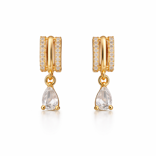 A pair of gold-plated huggie hoop earrings for women featuring a suspended clear pear-shaped crystal drop, shown on a clean white background.