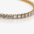 A close-view of a gold-plated tennis bracelet for women featuring a continuous row of brilliant round-cut stones, shown on a white background