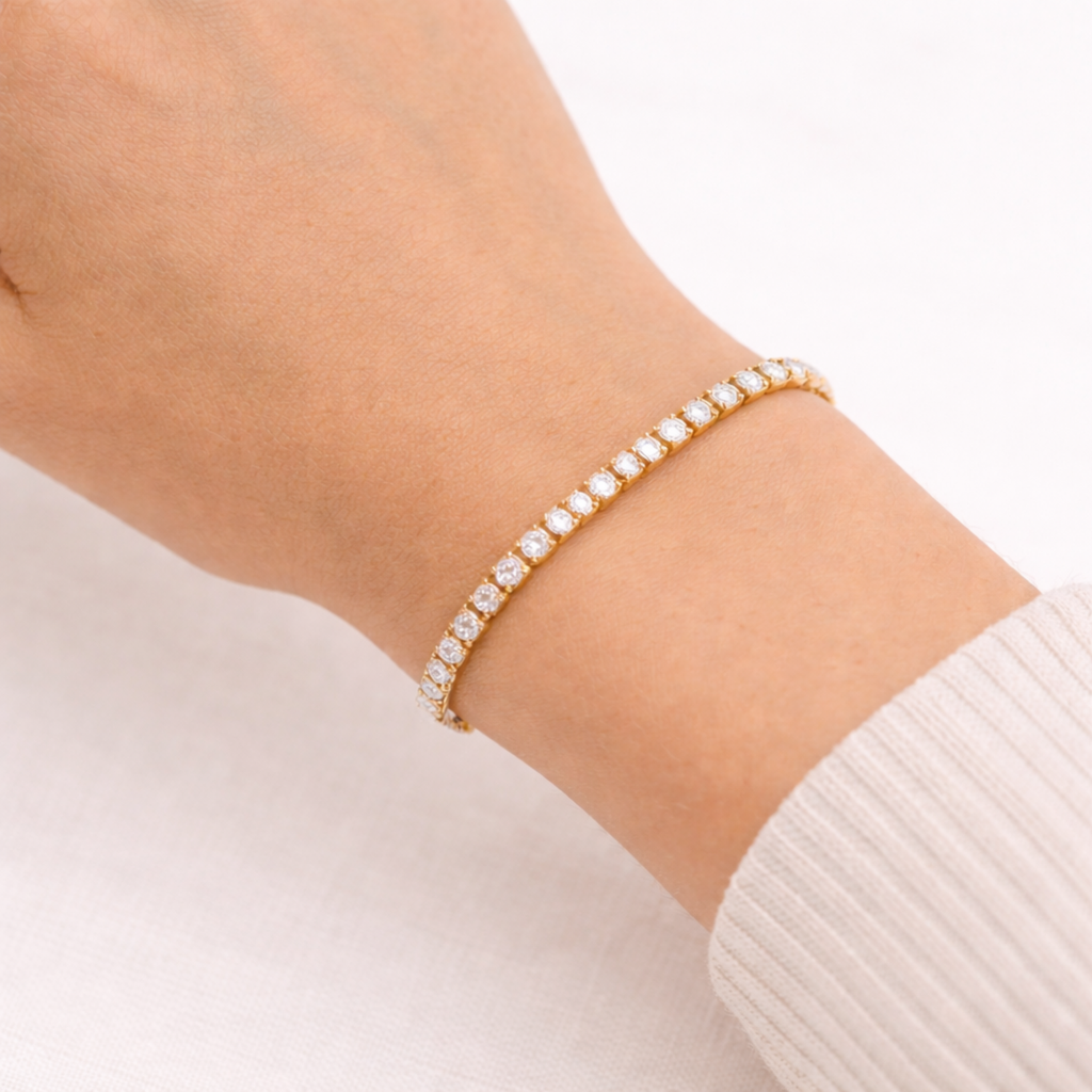 A classic gold-plated tennis bracelet for women on a wrist featuring a continuous row of brilliant round-cut stones, shown on a white background