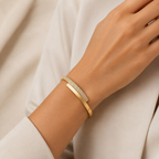 A gold-plated bypass bracelet for women featuring one side set with dense pavé crystals and a secure side-hinge clasp, shown on a model