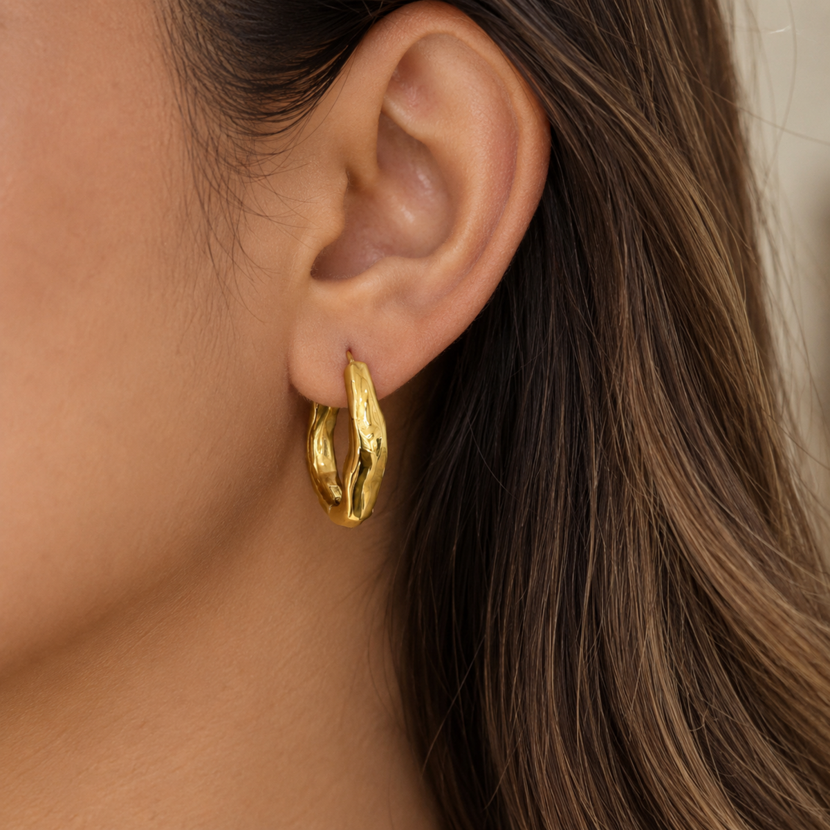 Sienna wavy hoop earrings for women with an organic curved design, 18K gold plated on a model ear