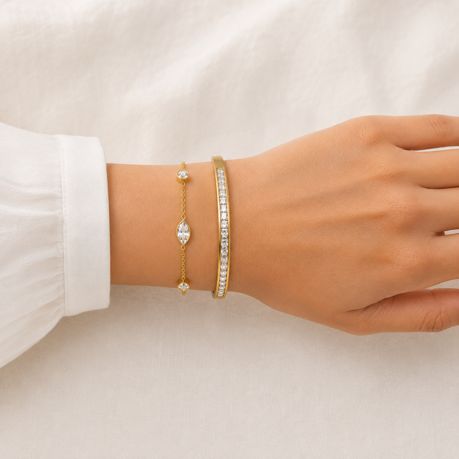 A two-piece gold-plated bracelet stack for women featuring a bangle and a delicate bezel-set crystal chain bracelet on a model