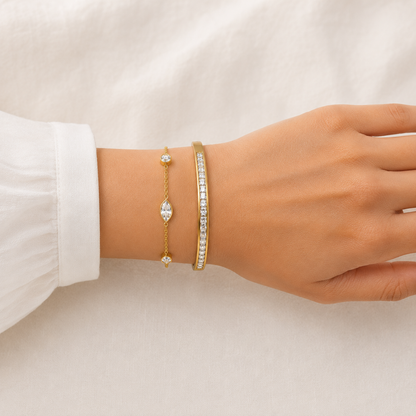A two-piece gold-plated bracelet stack for women featuring a bangle and a delicate bezel-set crystal chain bracelet on a model