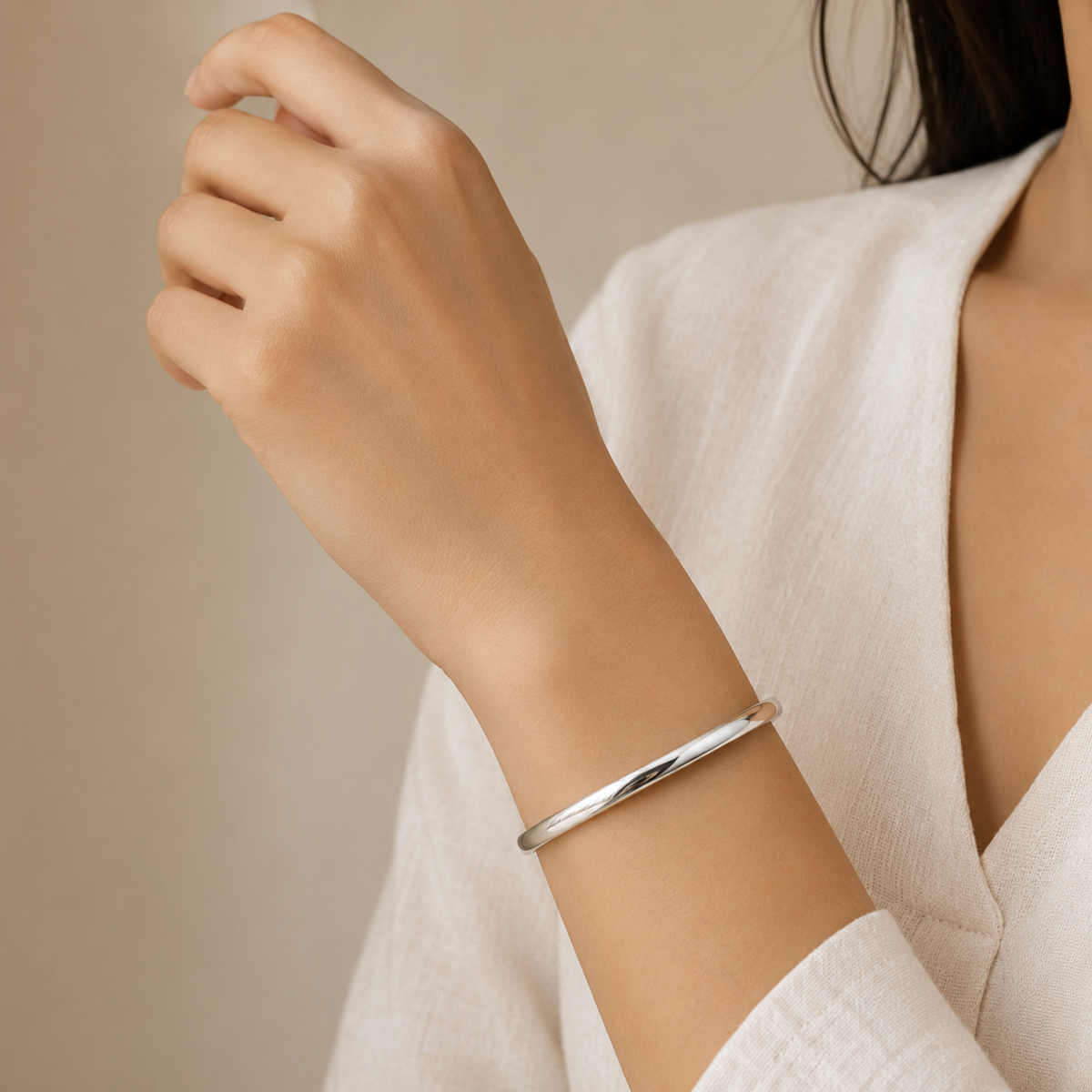 silver plated minimalist dome bangle bracelet for women with a smooth polished finish on a model hand