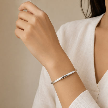 silver plated minimalist dome bangle bracelet for women with a smooth polished finish on a model hand