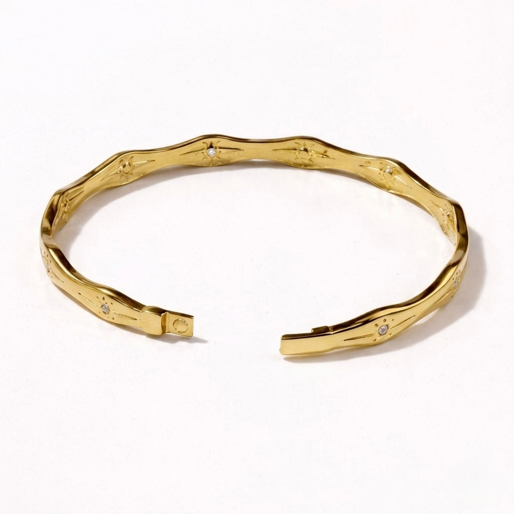 A premium gold-plated bangle for women featuring star-etched engravings and small crystals on a white background