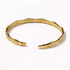 A premium gold-plated bangle for women featuring star-etched engravings and small crystals on a white background