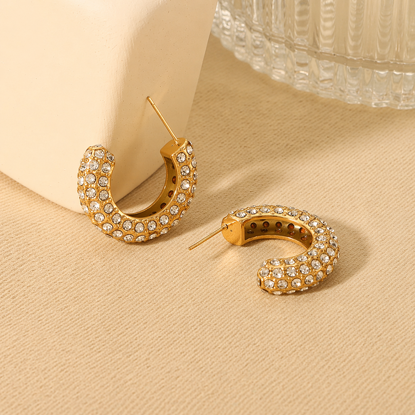A pair of gold-plated hoop earrings for women featuring a prominent princess-cut clear crystal and smaller round accents