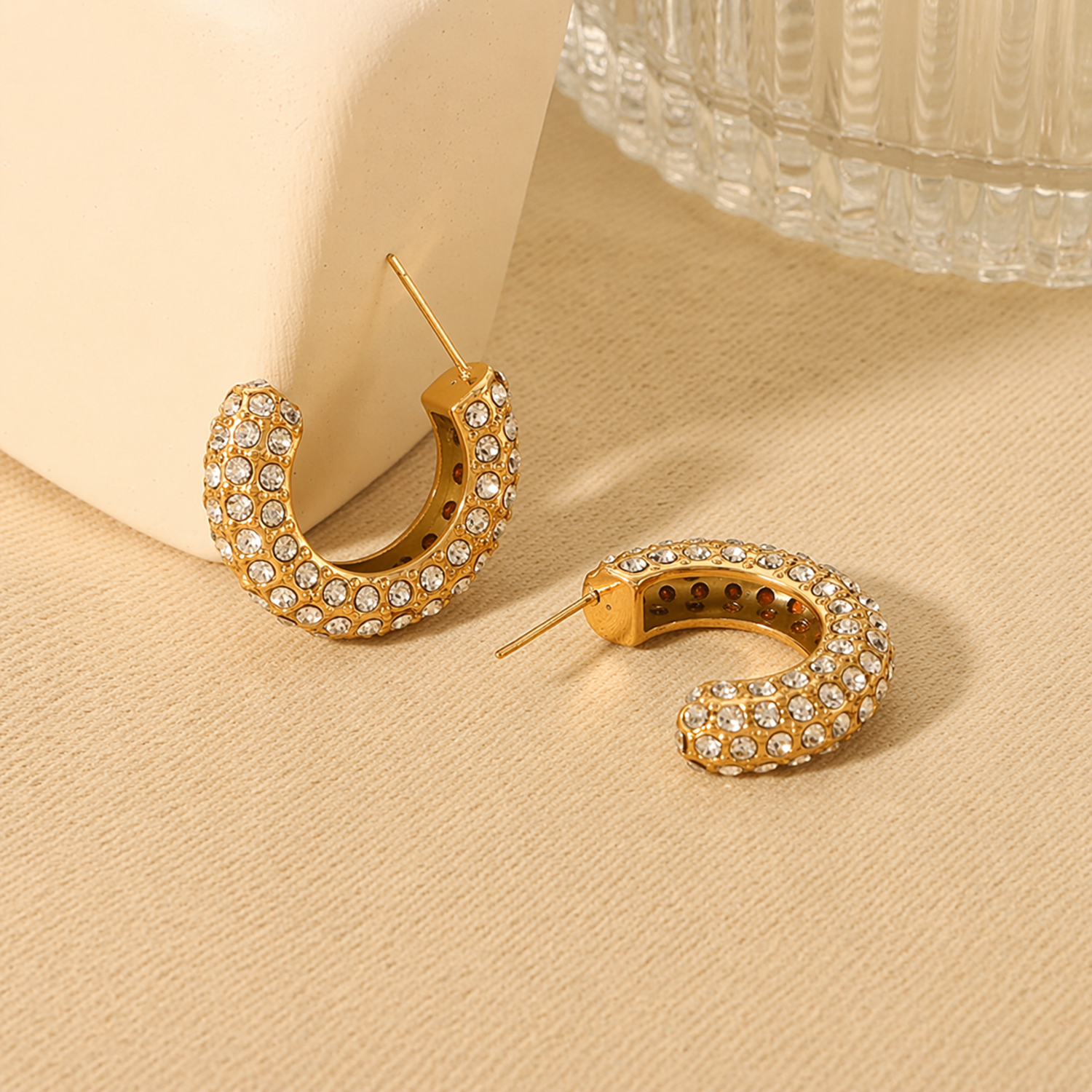 A pair of gold-plated hoop earrings for women featuring a prominent princess-cut clear crystal and smaller round accents
