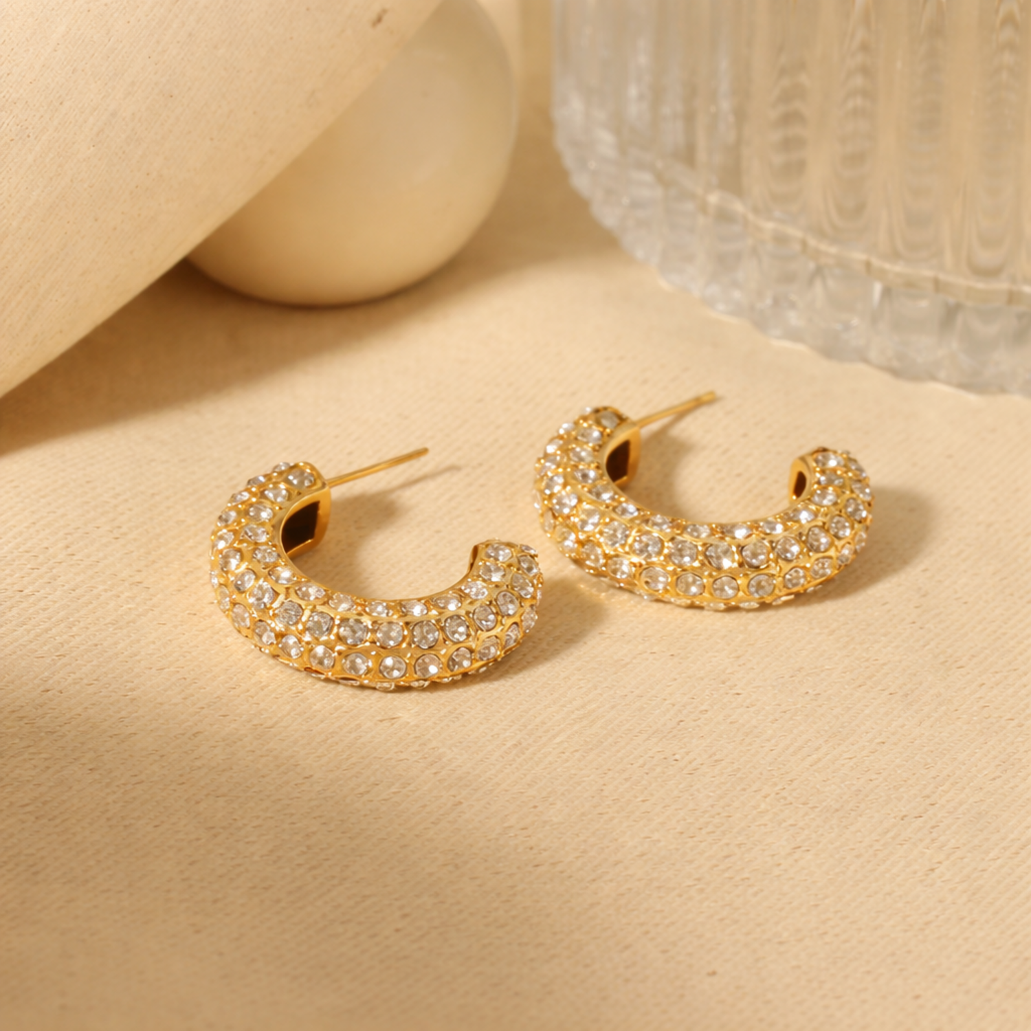 A pair of gold-plated hoop earrings for women featuring a prominent princess-cut clear crystal and smaller round accents