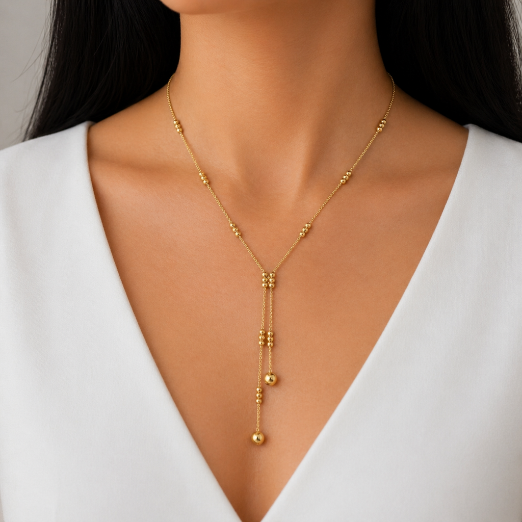 A gold-plated stainless steel chain for women featuring a double-strand Y-drop lariat design with gold beads, shown on a model