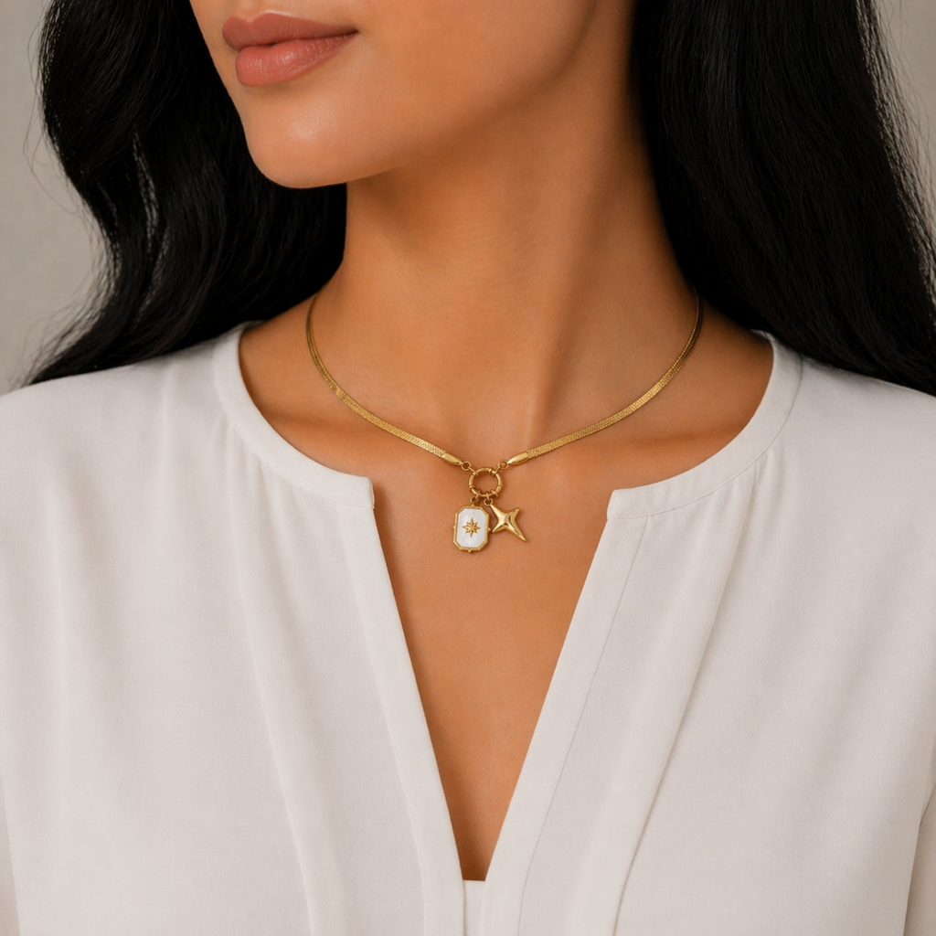 A gold-plated stainless steel chain for women featuring a flat snake chain and two celestial star charms, one with a pearl inlay, shown on a model