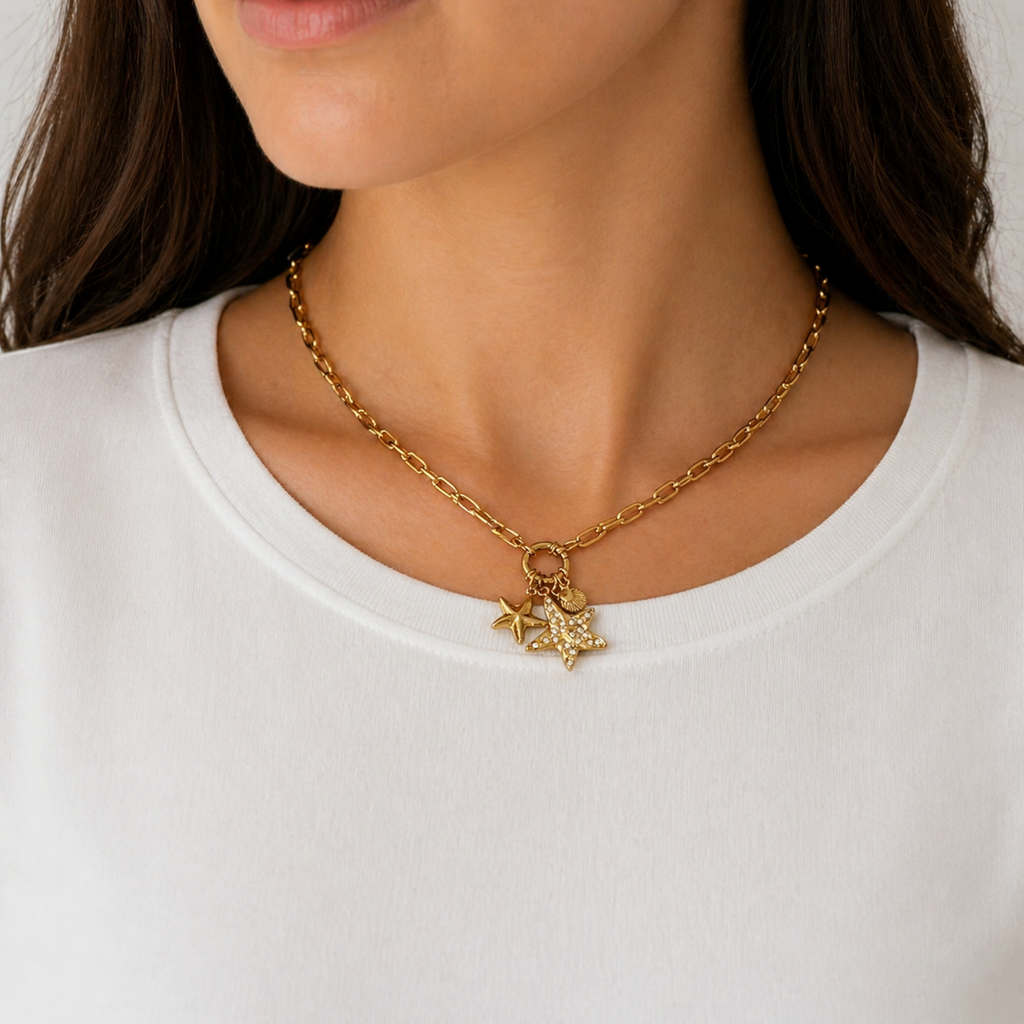 A gold-plated stainless steel chain for women featuring a paperclip link design with a crystal starfish and seashell charms, shown on a model