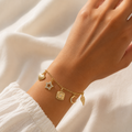 A close-view of a gold-plated charm bracelet for women featuring five dangling celestial charms including a sun, star, moon, heart, and wing.