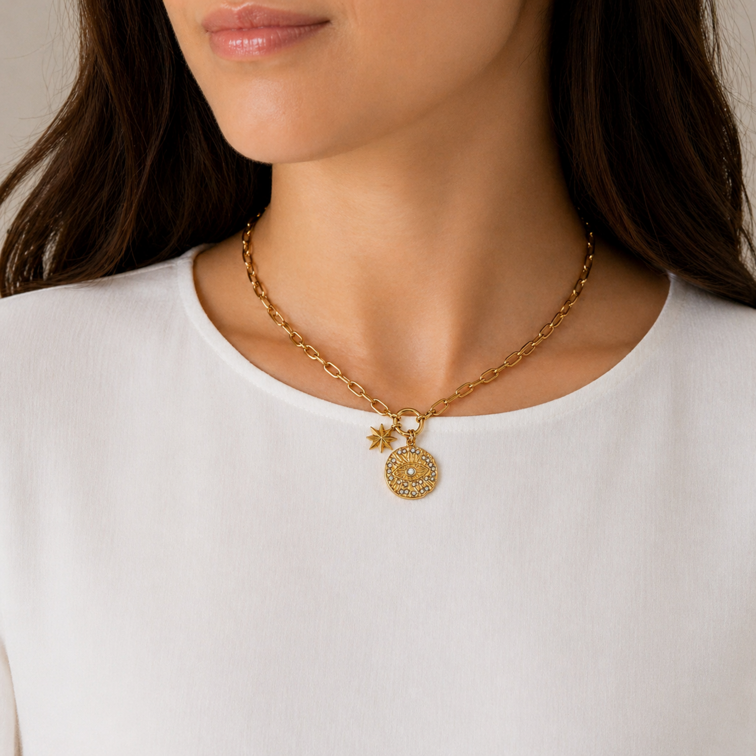 A gold-plated stainless steel chain for women featuring a paperclip link design with an evil eye medallion and star charm