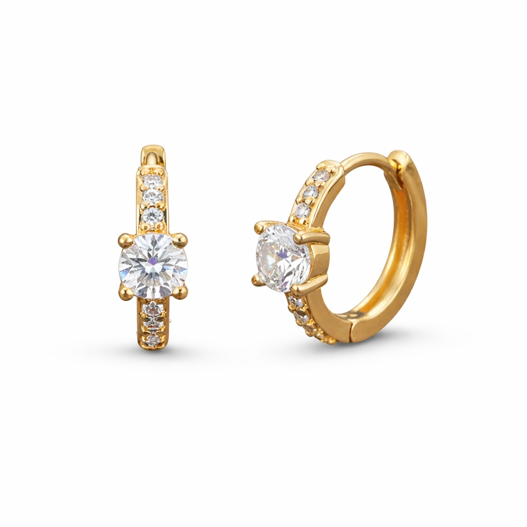 A pair of gold-plated huggie hoop earrings for women featuring a prominent brilliant-cut central stone and pave crystal accents, shown on a clean white background