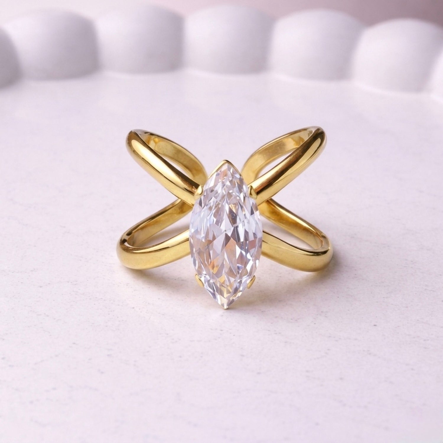 Gold plated adjustable statement ring for women featuring a large white-cut white stone crystal centered on a unique intersecting X-shaped band, displayed on a white background.