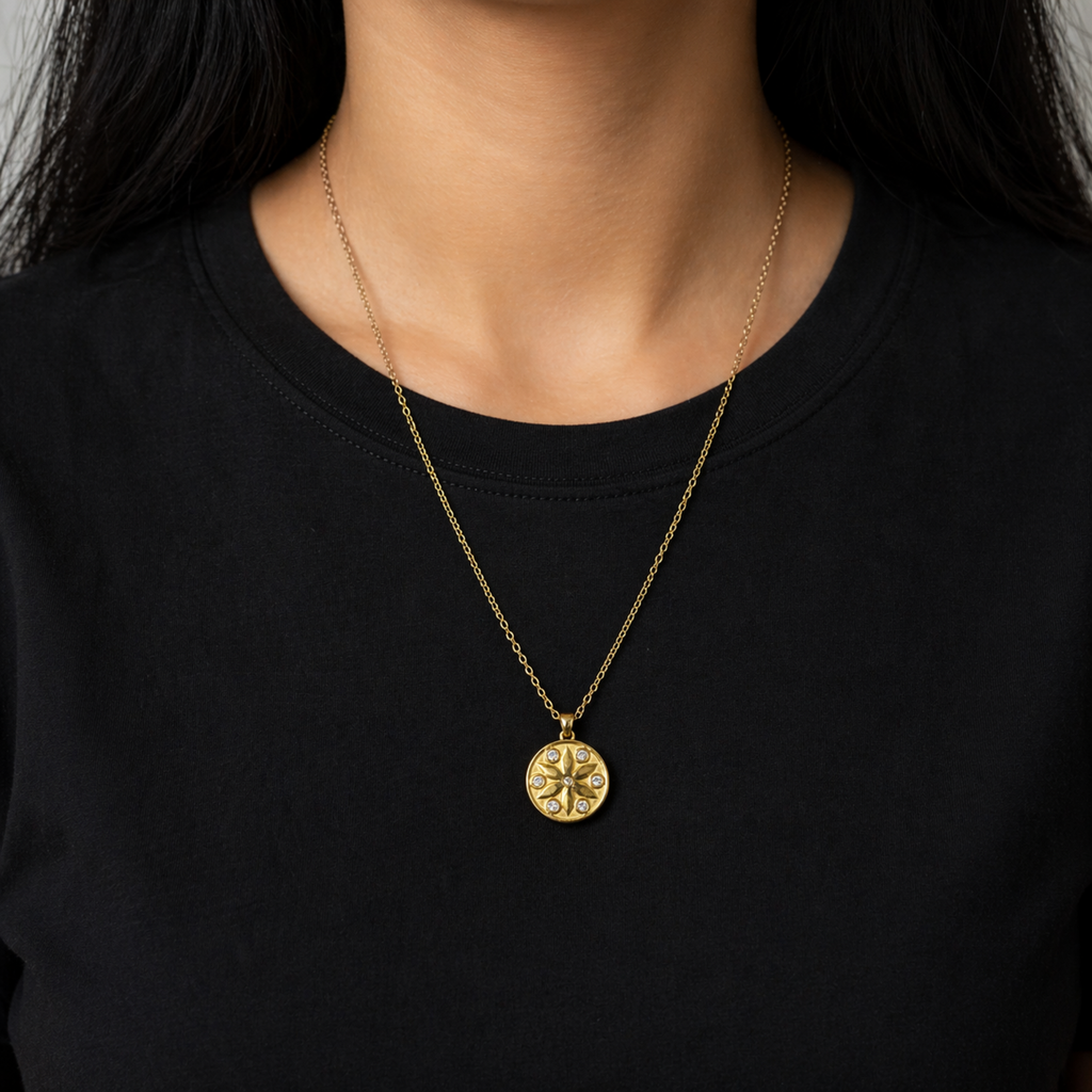 A gold-plated stainless steel chain for women featuring a circular medallion pendant with an embossed star pattern and seven sparkling crystals on a model