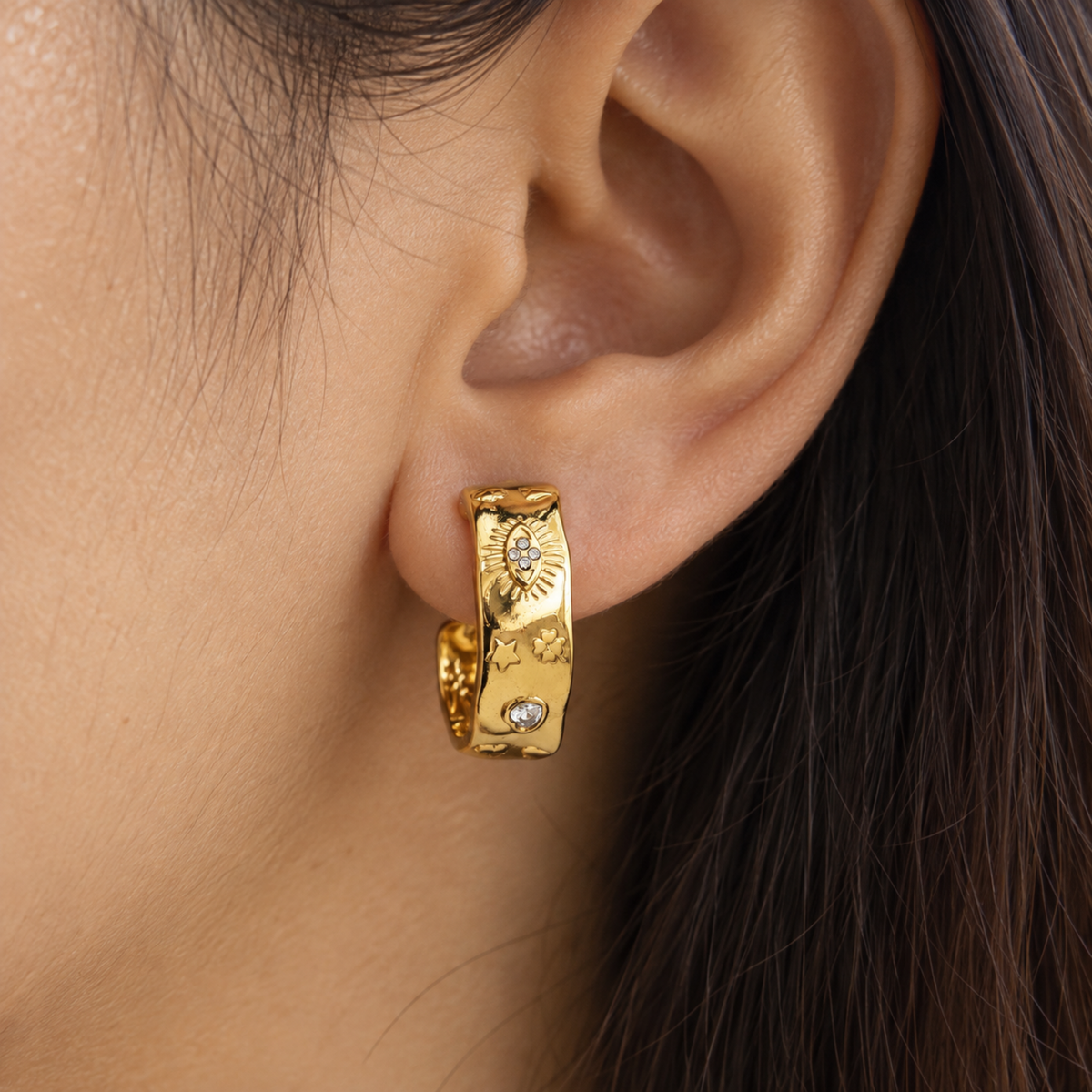 Gold sunburst hoop earrings for women with celestial star, heart and floral motifs and sparkling crystal accents on a model