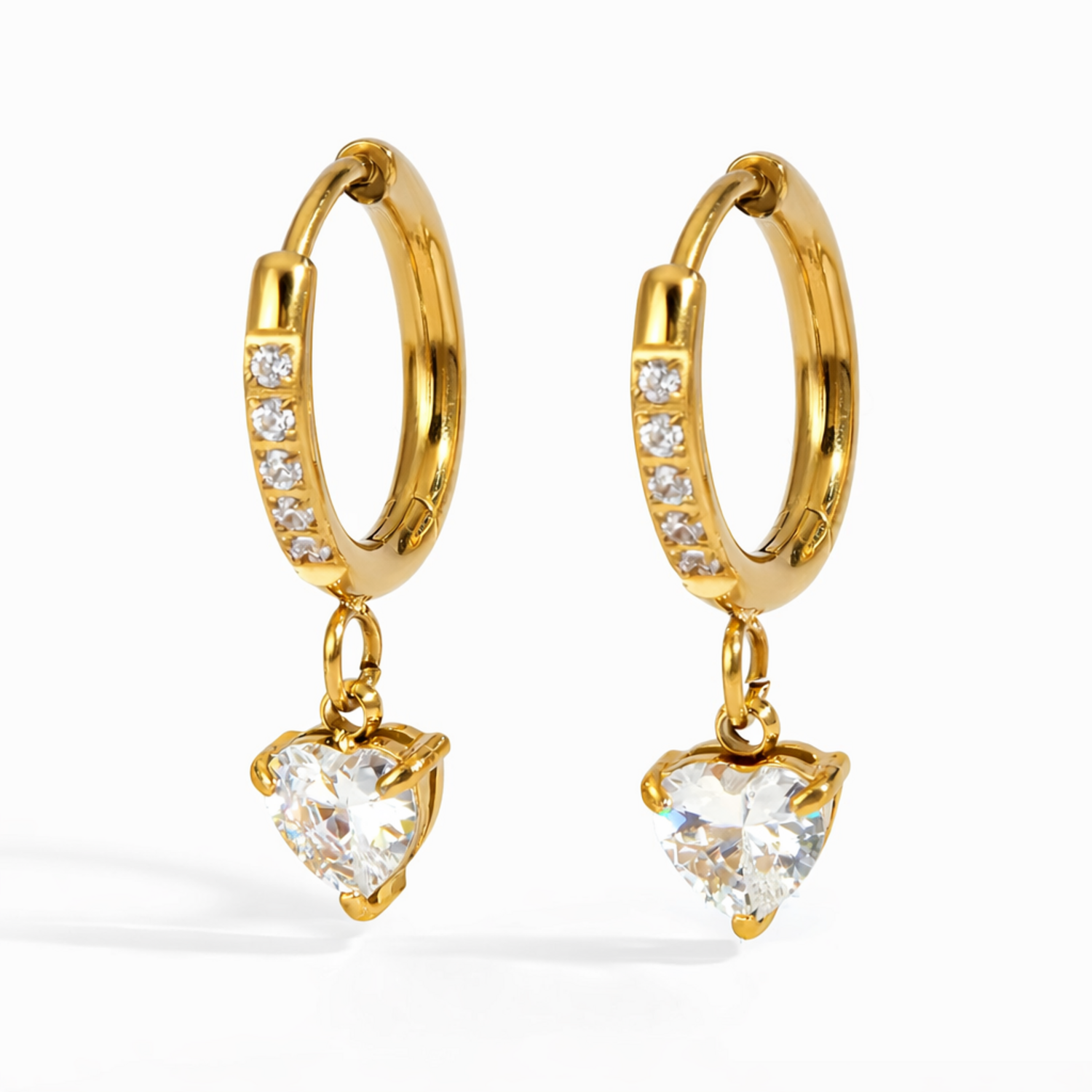 A pair of gold-plated hoop earrings for women featuring a sparkling heart-cut crystal drop, shown on a white background
