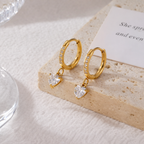 A close-view of a pair of gold-plated hoop earrings for women featuring a sparkling heart-cut crystal drop