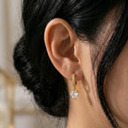 A gold-plated hoop earrings for women featuring a sparkling heart-cut crystal drop, shown on a model