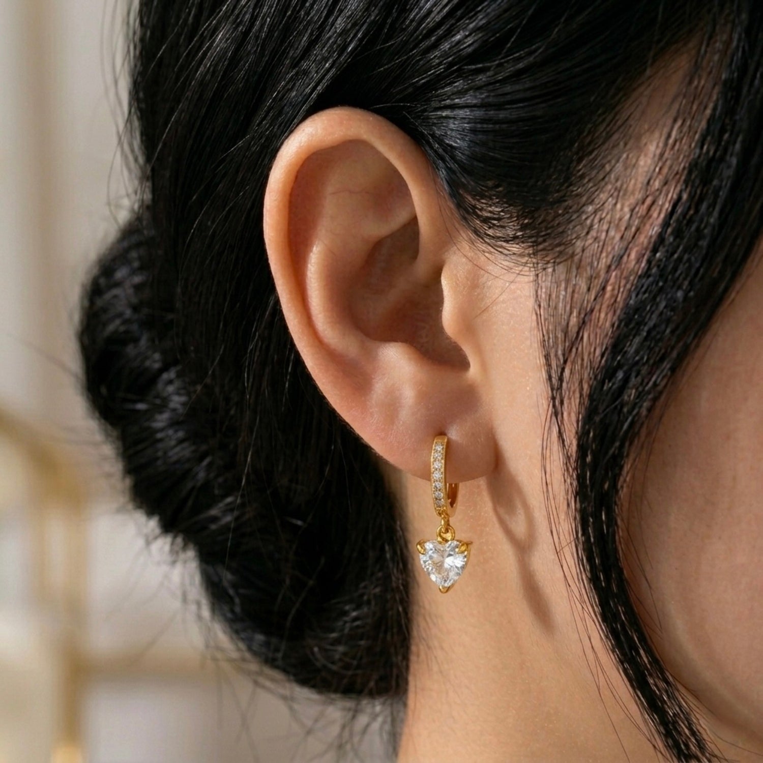 A gold-plated hoop earrings for women featuring a sparkling heart-cut crystal drop, shown on a model