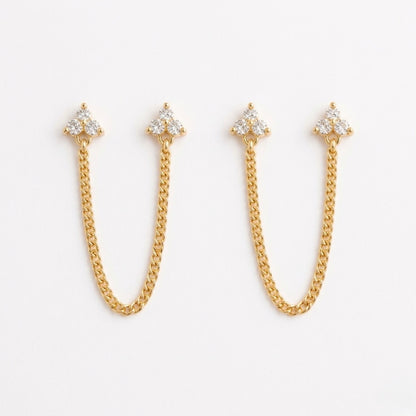 A pair of gold-plated ear chain earrings for women featuring two triple-stone white stone  blossom studs connected by a shimmering gold chain on a white background