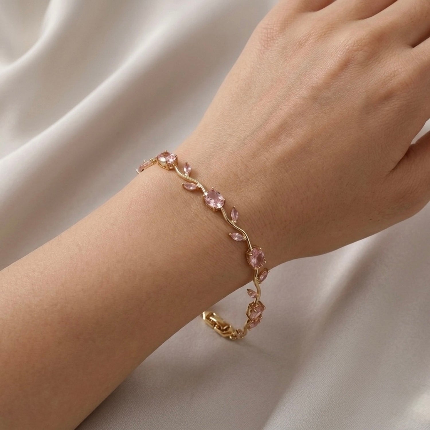 A close-view of a  gold-plated tulip vine chain bracelet for women featuring soft pink oval and marquise-cut stones, shown on a clean white background