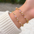 A gold-plated tulip vine chain bracelet for women featuring soft pink oval and marquise-cut stones, shown on a model