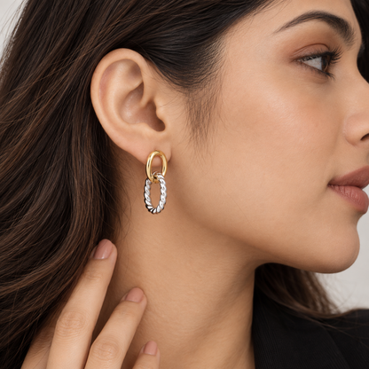 A close-up of a woman wearing a gold hoop earring with a textured black-and-white patterned lower half, shown against her ear and neck.