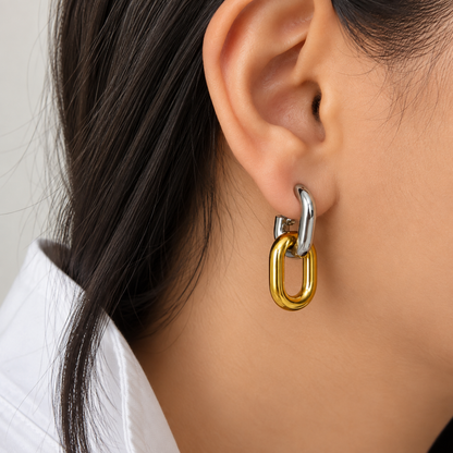 Two-tone gold and silver interlocking drop earrings for women with a sleek elongated loop design and polished finish on a model