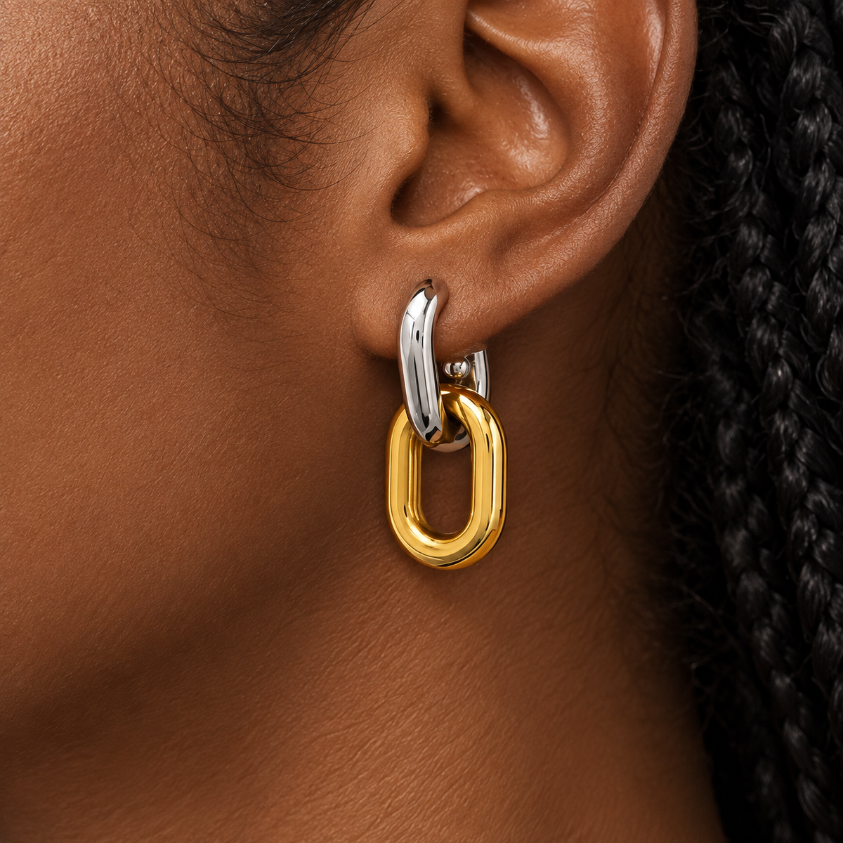 Two-tone gold and silver interlocking drop earrings for women with a sleek elongated loop design and polished finish on a model
