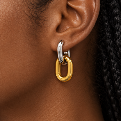 Two-tone gold and silver interlocking drop earrings for women with a sleek elongated loop design and polished finish on a model