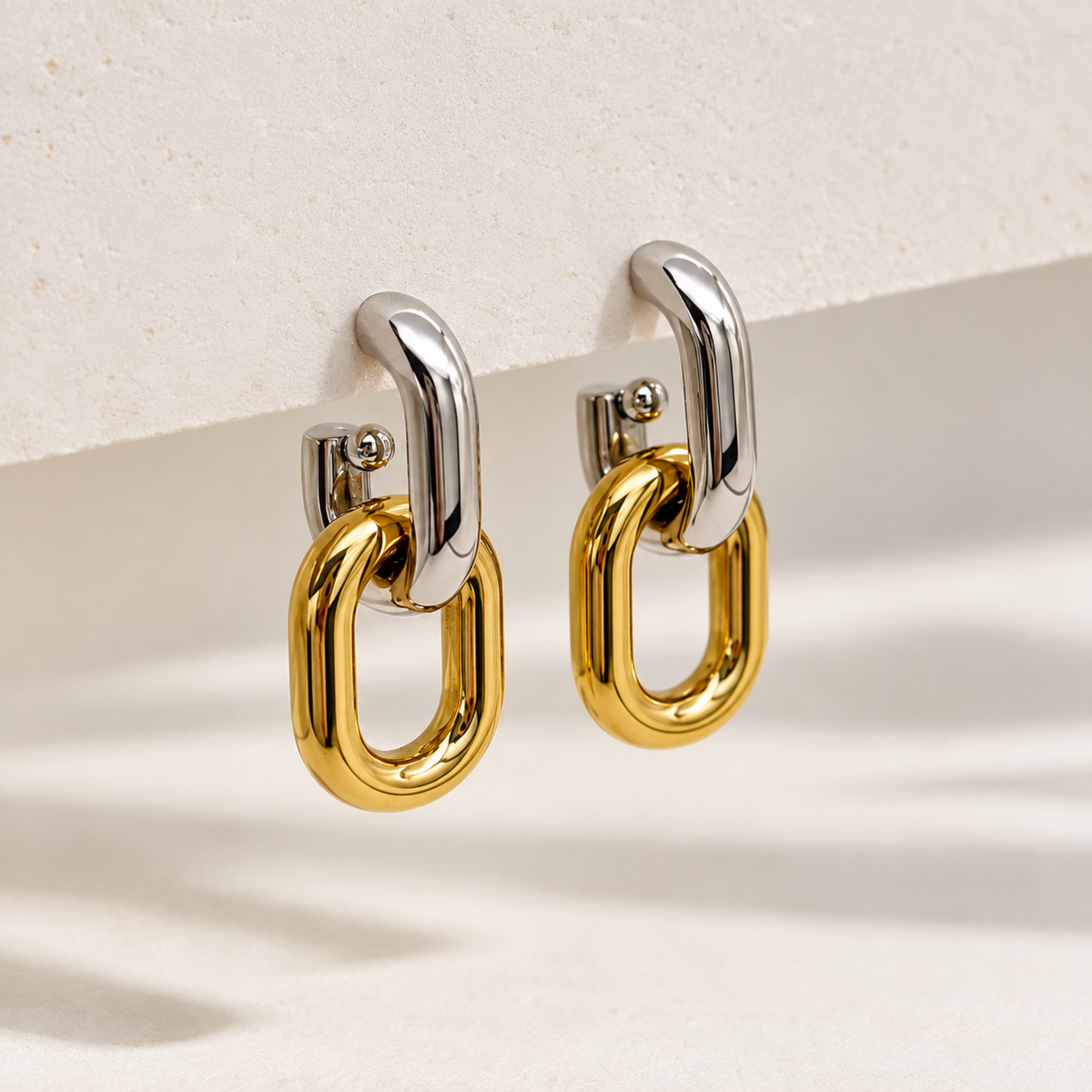 Two-tone gold and silver interlocking drop earrings for women with a sleek elongated loop design and polished finish on display