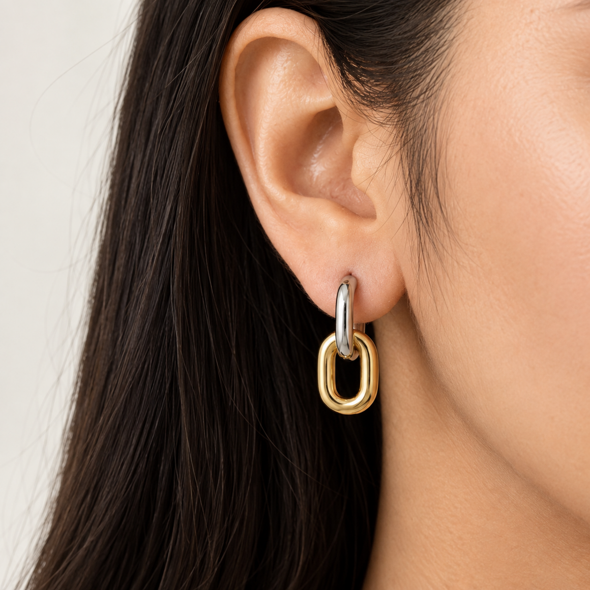 Two-tone gold and silver interlocking drop earrings for women with a sleek elongated loop design and polished finish on a model