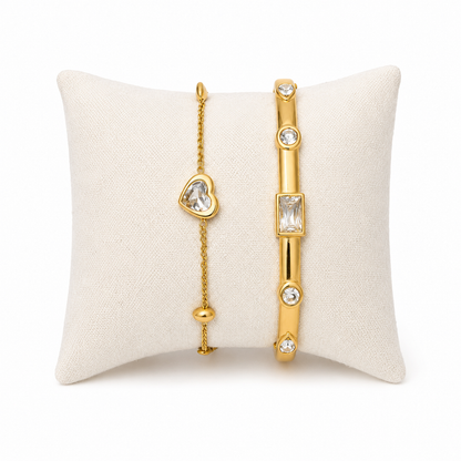 A premium two-piece gold-plated bracelet stack for women featuring a gold baguette station bangle and a fine link chain with a single heart crystal charm