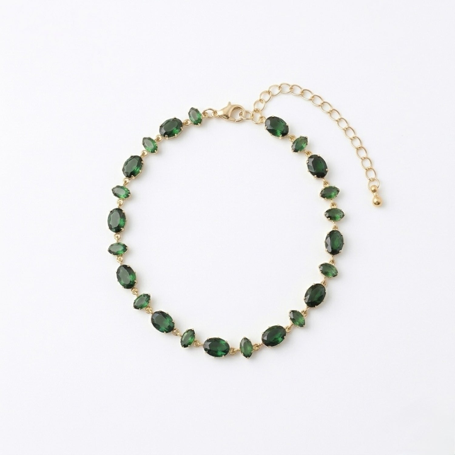 A gold-plated chain bracelet for women featuring a continuous row of deep emerald green oval-cut stones on a clean white background