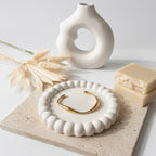 A minimalist gold-plated twisted cuff bracelet for women featuring wave design displayed on a ceramic dish.