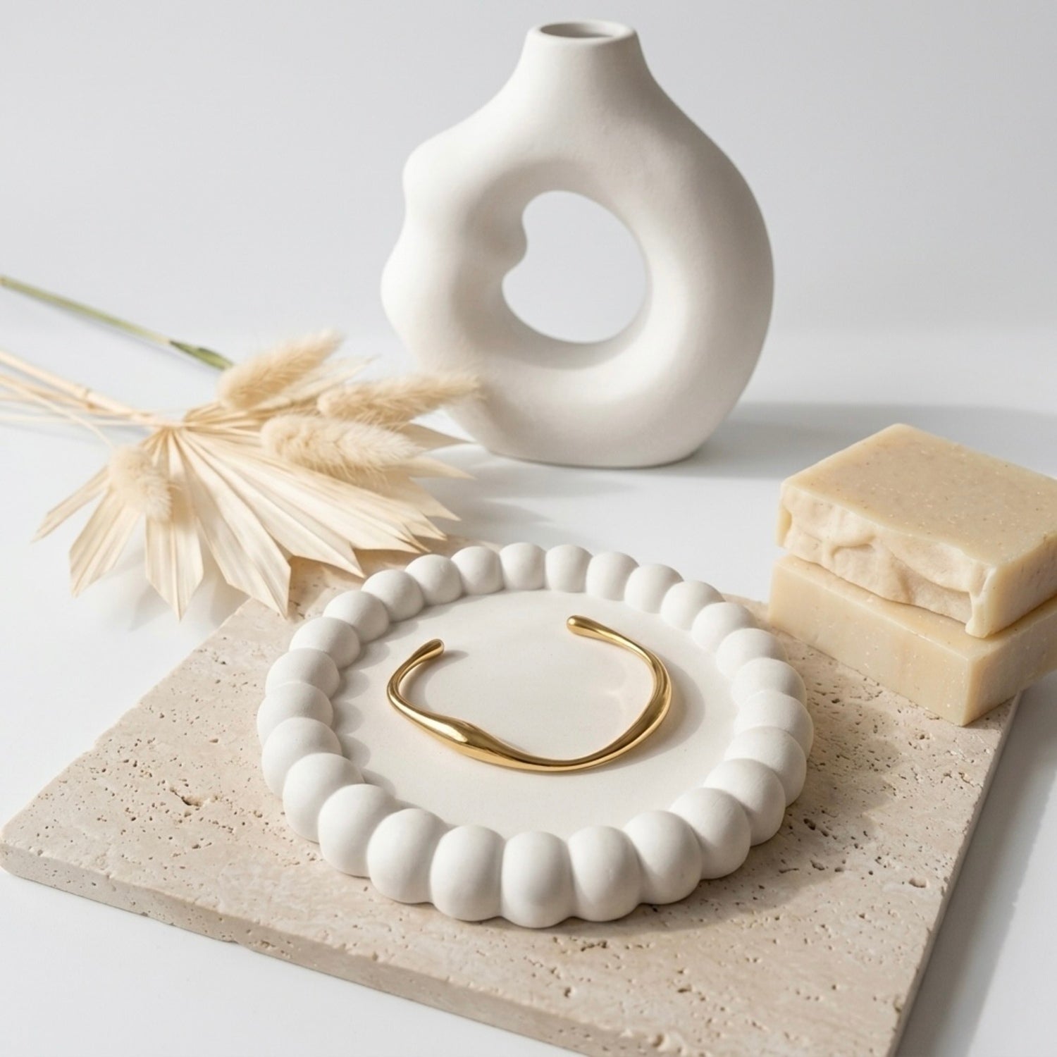 A minimalist gold-plated twisted cuff bracelet for women featuring wave design displayed on a ceramic dish.