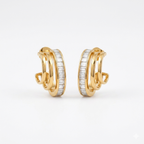 A pair of gold-plated triple-band hoop earrings for women featuring a central row of clear baguette crystals, shown on a clean white background.