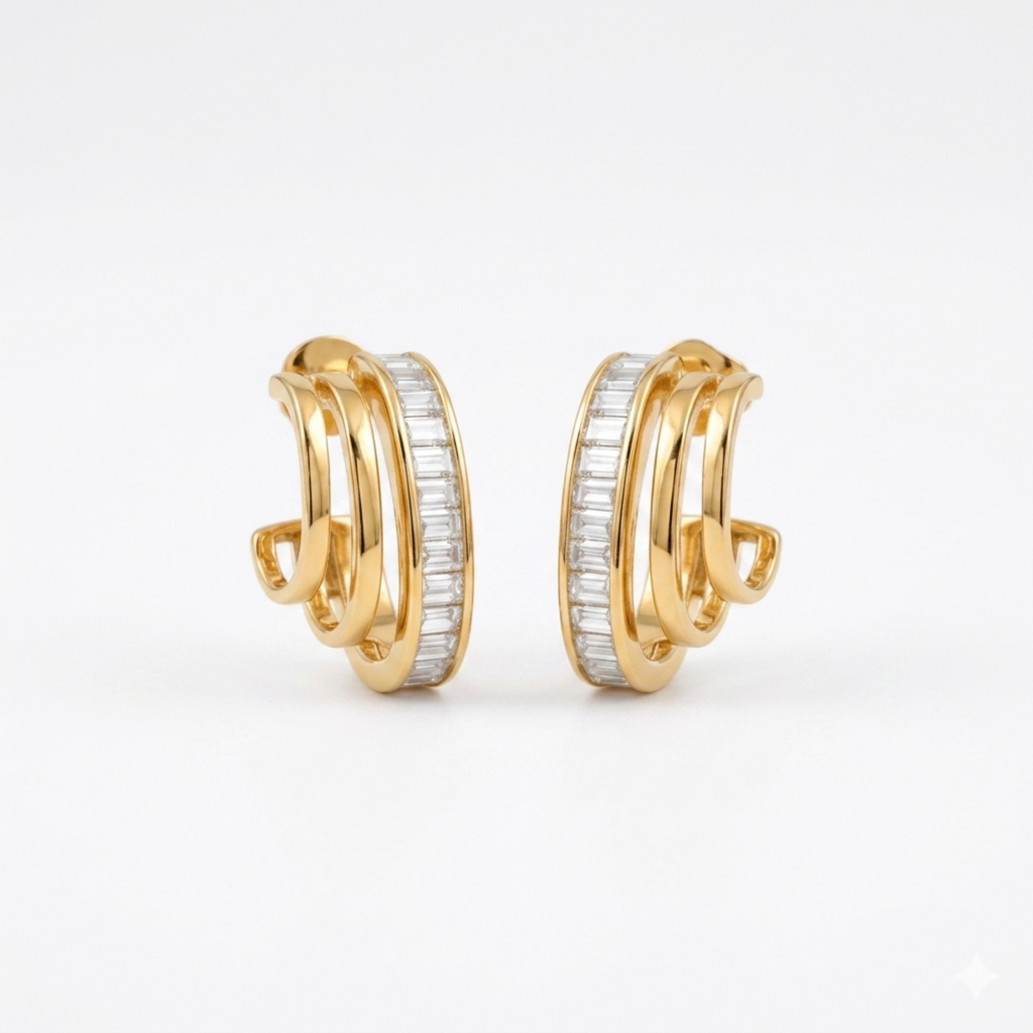 A pair of gold-plated triple-band hoop earrings for women featuring a central row of clear baguette crystals, shown on a clean white background.