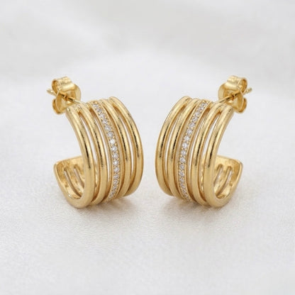A pair of gold-plated multi-band hoop earrings for women featuring a central row of clear pavé crystals, shown on a white background.