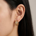 A gold-plated multi-band hoop earrings for women featuring a central row of clear pavé crystals, shown on a model