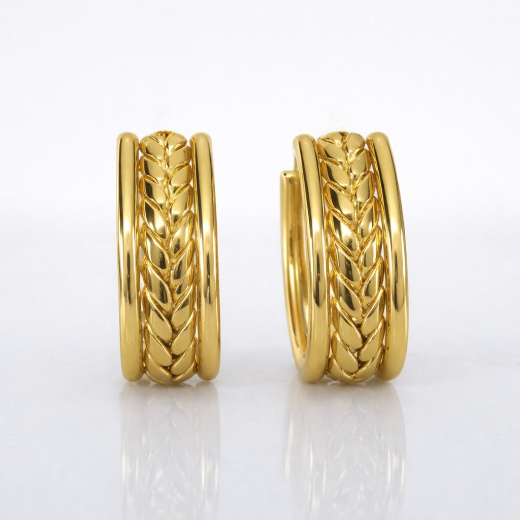 A close-view of a pair of gold-plated wide-band open hoop earrings for women featuring a detailed central braided wheat design, shown on a clean white background.