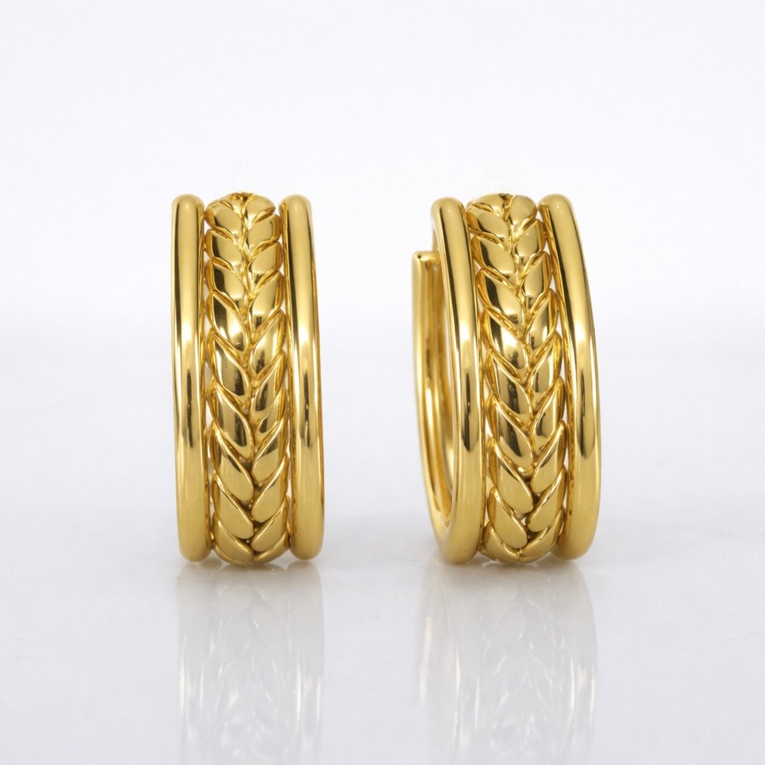A close-view of a pair of gold-plated wide-band open hoop earrings for women featuring a detailed central braided wheat design, shown on a clean white background.