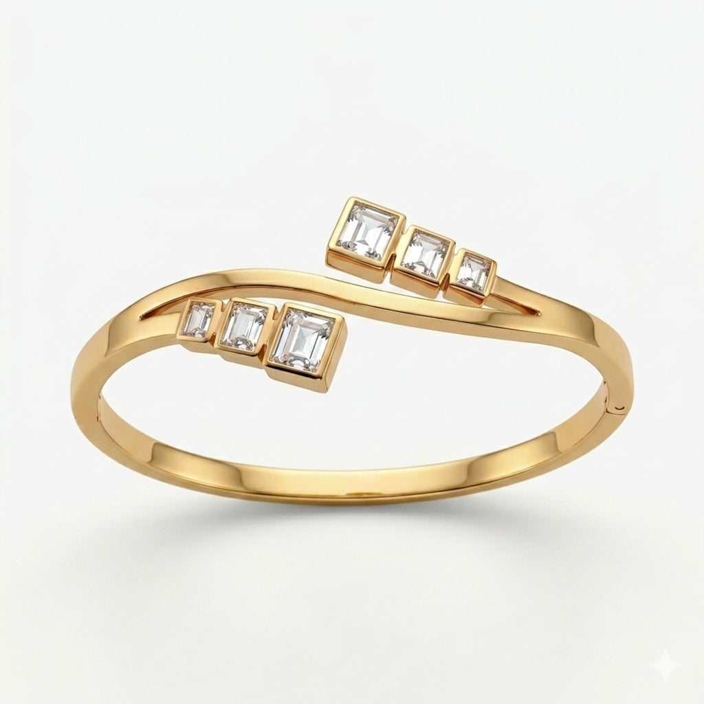 A gold-plated crossover bypass bangle for women featuring graduated baguette-cut crystals and a secure side-clasp.